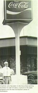 man standing in front of a large coca cola sign
