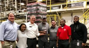 group of men and women coca cola united employees smiling in mobile, al factory